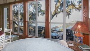 A room with large windows, a view of a dock, and a lamp on a table. - Waterfront Bay property with private beach and pier! (Gulf Shores)