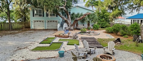 Un patio trasero con terraza de madera, mobiliario exterior y una chimenea.