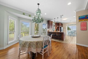 A dining area with a round table, chairs, and a chandelier. - Waterfront Bay property with private beach and pier! (Gulf Shores)