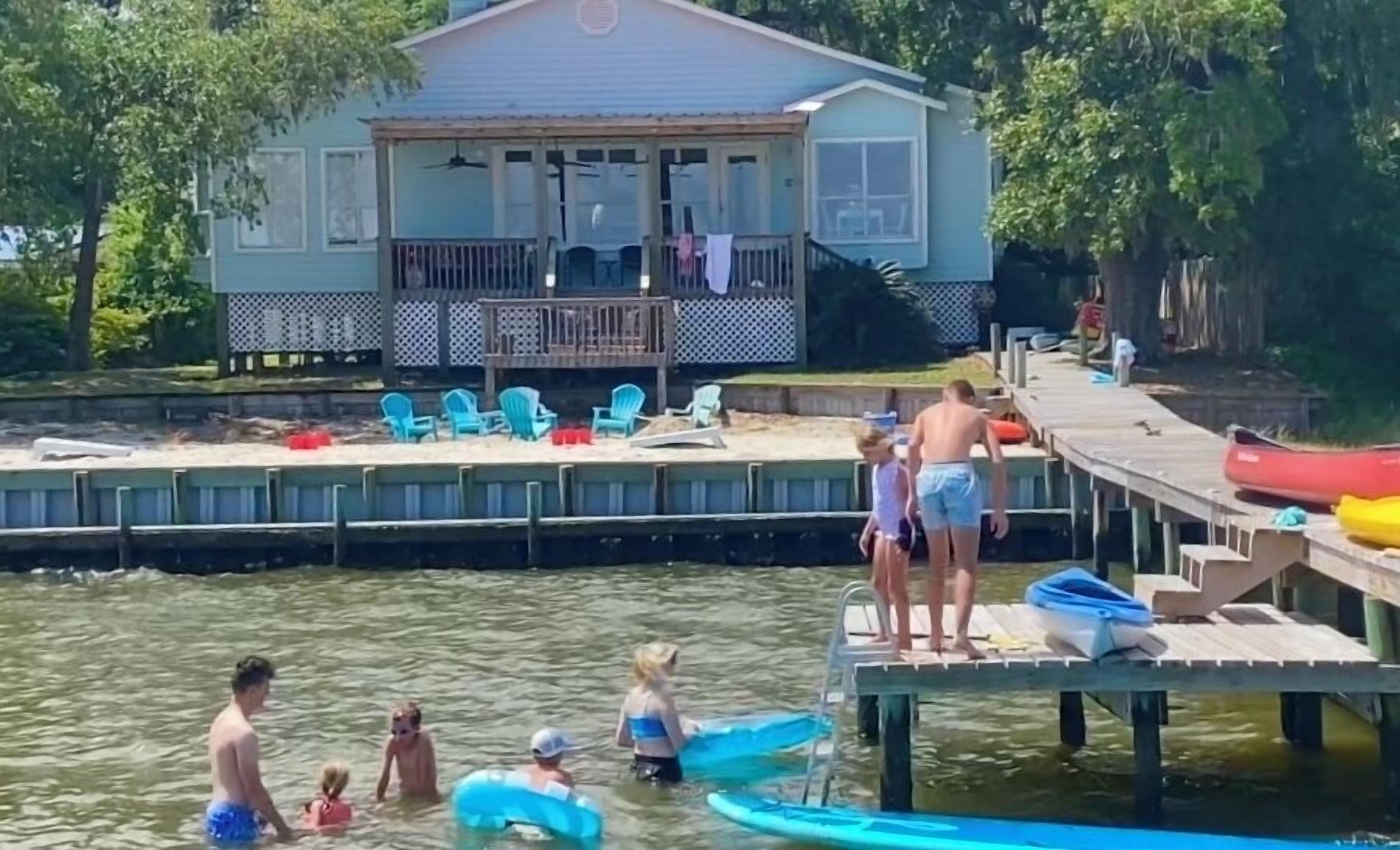 A dock with chairs and a house in the background.