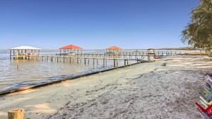 A beach with wooden walkways and covered seating areas. - Waterfront Bay property with private beach and pier! (Gulf Shores)