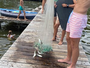 Eine Holzsteg mit Personen, einem Kajak und einem Fischernetz voller Fische.