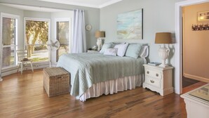 A bedroom with a bed, nightstands, a lamp, a chair, a window with blinds, and a ceiling fan. - Waterfront Bay property with private beach and pier! (Gulf Shores)