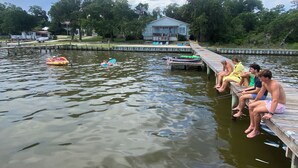 A dock with people sitting and a small house in the background.
