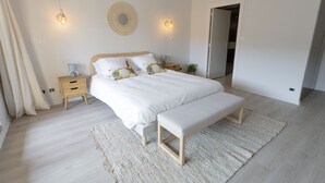 A modern bedroom with a large bed, bedside tables, a bench, and a wall-mounted light fixture. - Superbe 120m2 - 2chambres + 2sdb, 3 Grds Balcons (Annecy)