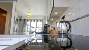 A modern kitchen with a reflective countertop, a coffee maker, and a hanging light fixture. - Superbe 120m2 - 2chambres + 2sdb, 3 Grds Balcons (Annecy)