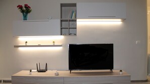 Un meuble de divertissement moderne doté d’un téléviseur à écran plat, d’un éclairage intégré et d’un design minimaliste.