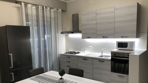 Une cuisine moderne équipée d’un four à micro-ondes encastré, d’une cuisinière à gaz et d’un évier en acier inoxydable.