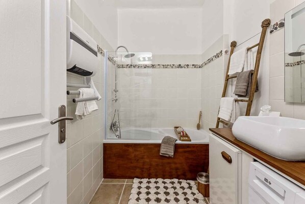 A modern bathroom with a bathtub, a wooden vanity, and a glass shower enclosure.