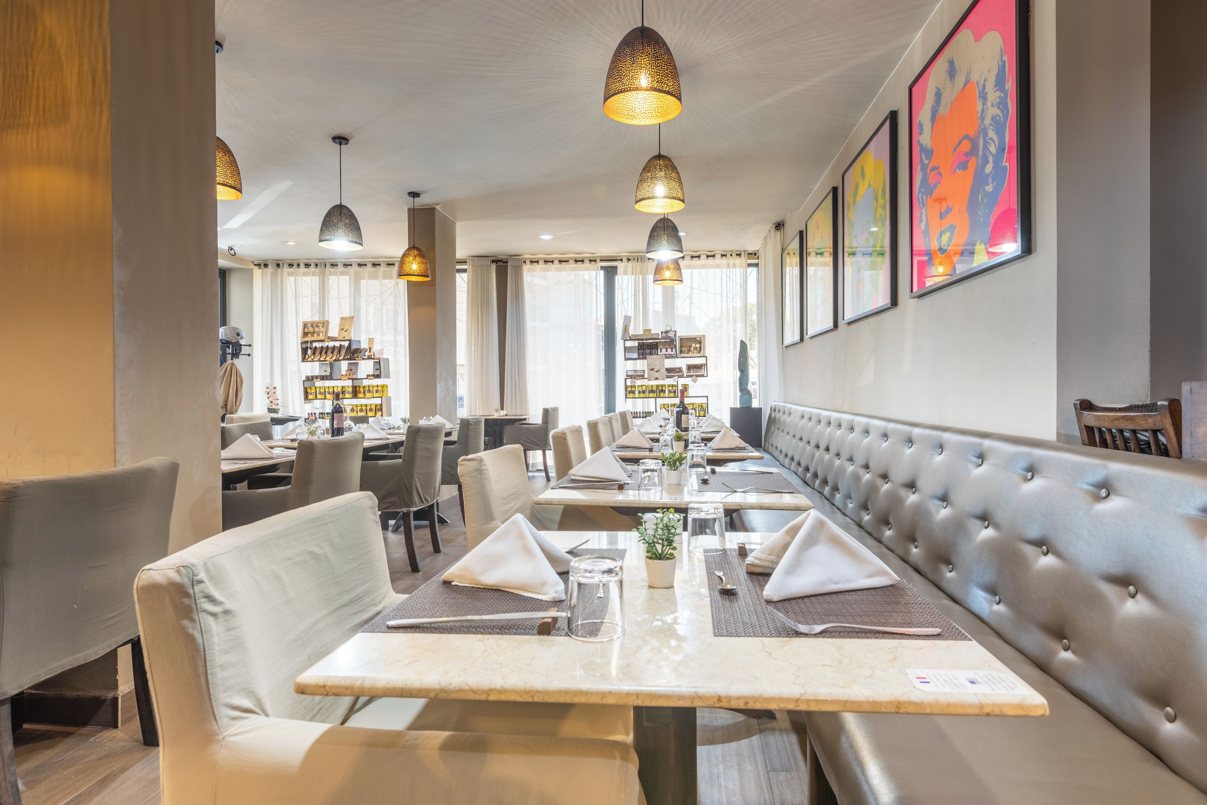 A restaurant with long communal tables, cushioned booths, and pendant lighting.