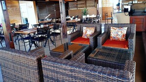 Un restaurant doté de mobilier en osier, de poutres en bois et d’un espace bar.