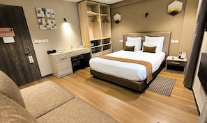 A modern hotel room with a large bed, a desk, a wardrobe, and a bedside table. - Fly Inn Madagascar Hotel (Antananarivo)