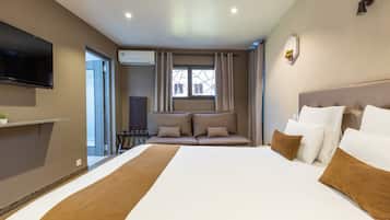 Une chambre d’hôtel avec un grand lit, un téléviseur à écran plat fixé au mur, une fenêtre avec des rideaux et une table de chevet.