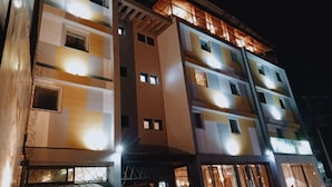 Un hôtel à plusieurs étages, doté de fenêtres et de balcons illuminés.