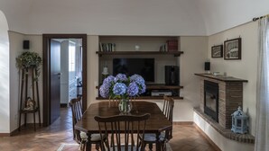 A dining area with a wooden table, chairs, a vase of flowers, a television, and a fireplace. - De Angelis House | Amalfi Coast Sea View Terrace (Sant' Agnello ( Fraz. Colli di Fontanelle))