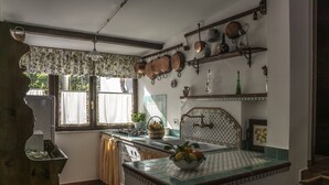 A kitchen with a central island, a window with curtains, and various kitchen utensils on the wall. - De Angelis House | Amalfi Coast Sea View Terrace (Sant' Agnello ( Fraz. Colli di Fontanelle))