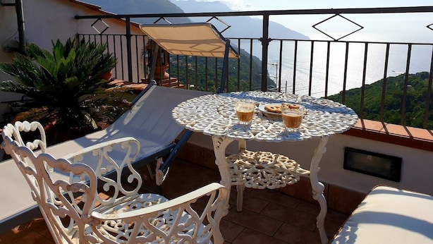 A balcony with a table, chairs, and a sun lounger. - De Angelis House | Amalfi Coast Sea View Terrace (Sant' Agnello ( Fraz. Colli di Fontanelle))