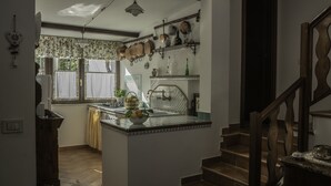 A kitchen with a central island, a window with curtains, and a staircase leading to another level. - De Angelis House | Amalfi Coast Sea View Terrace (Sant' Agnello ( Fraz. Colli di Fontanelle))