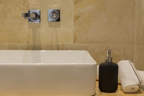 Une salle de bain avec une baignoire blanche, une bouteille noire et une serviette blanche posées sur une surface en bois.