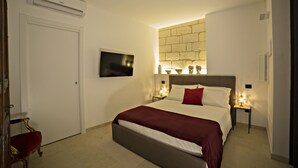 Hotelkamer met een bed, een televisie, een ingebouwde airconditioner en een klein tafeltje met een lamp.
