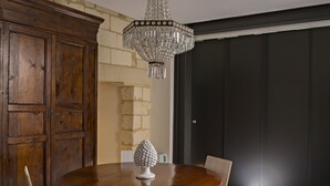 Een eetgedeelte met een houten tafel, stoelen, een kroonluchter en een kast.