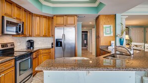 A modern kitchen with wooden cabinets, stainless steel appliances, and a granite countertop. - MAKE OFFER JULY 5-10 Stunning Gulf Views, 3 Bed 3 Bath Silver Shells Resort (Destin)
