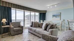 A living room with a sofa, armchairs, a small table with a lamp, and a view of the outside balcony. - MAKE OFFER JULY 5-10 Stunning Gulf Views, 3 Bed 3 Bath Silver Shells Resort (Destin)