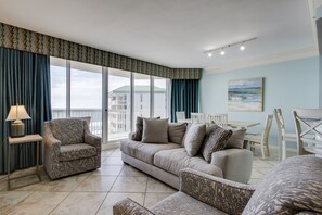 A living room with a sofa, armchairs, a small table with a lamp, and a view of the outside balcony. - MAKE OFFER JULY 5-10 Stunning Gulf Views, 3 Bed 3 Bath Silver Shells Resort (Destin)