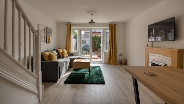 Un salon comprenant un canapé, une table basse, une cheminée et un téléviseur fixé au mur.
