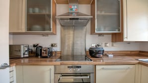 Une cuisine moderne équipée d’un four encastré, d’un grille-pain, d’une bouilloire et d’une hotte aspirante.