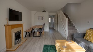 Un salon moderne avec une cheminée, un coin repas et un escalier.