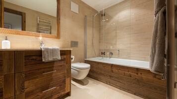 A modern bathroom with a wooden vanity, a toilet, a bathtub, and a glass shower enclosure.