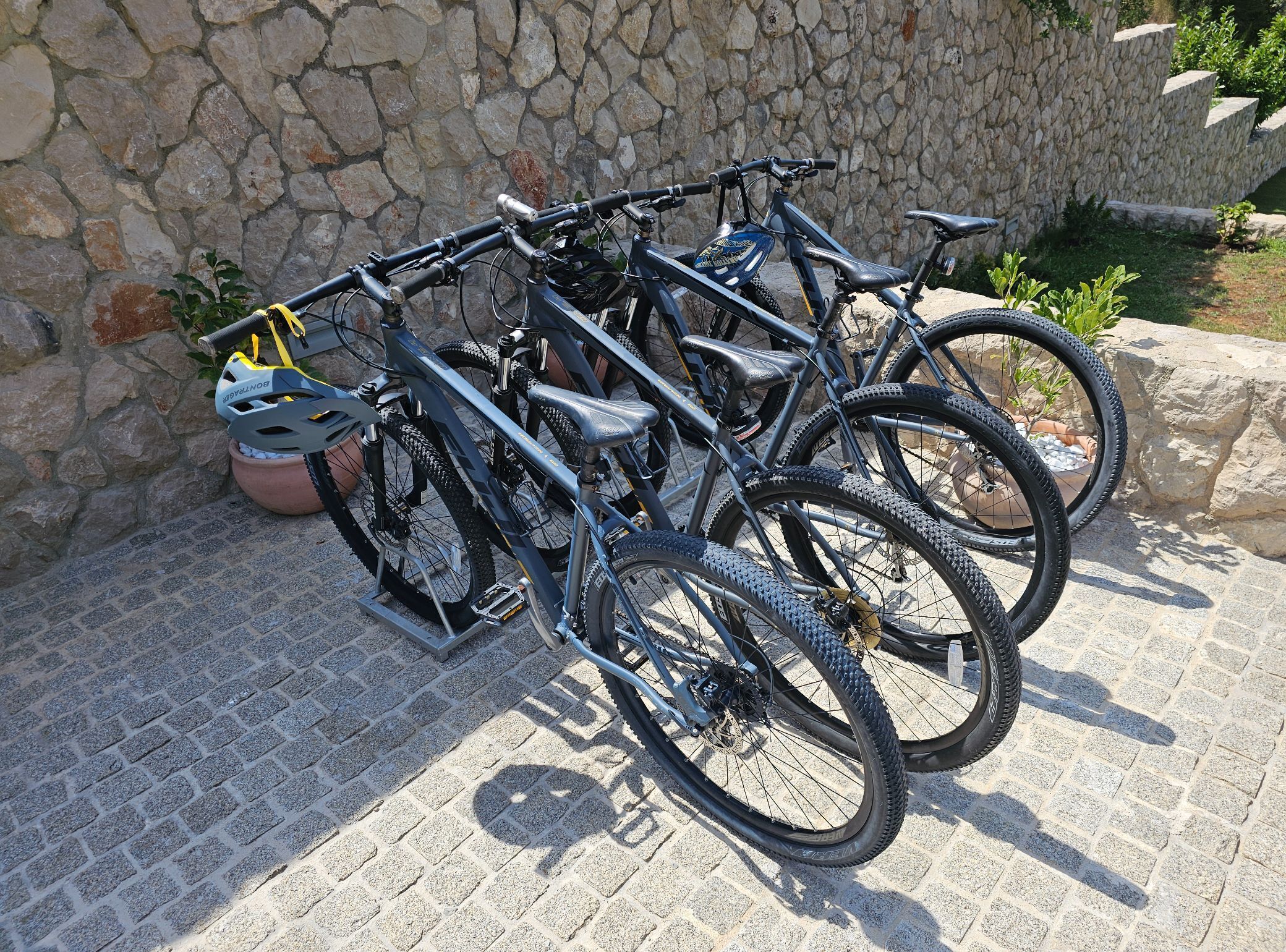 Un mur de pierre avec un support à vélos où sont rangées plusieurs bicyclettes.