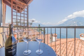 A table with a bottle and two glasses, overlooking a coastal view with buildings and a mountain.