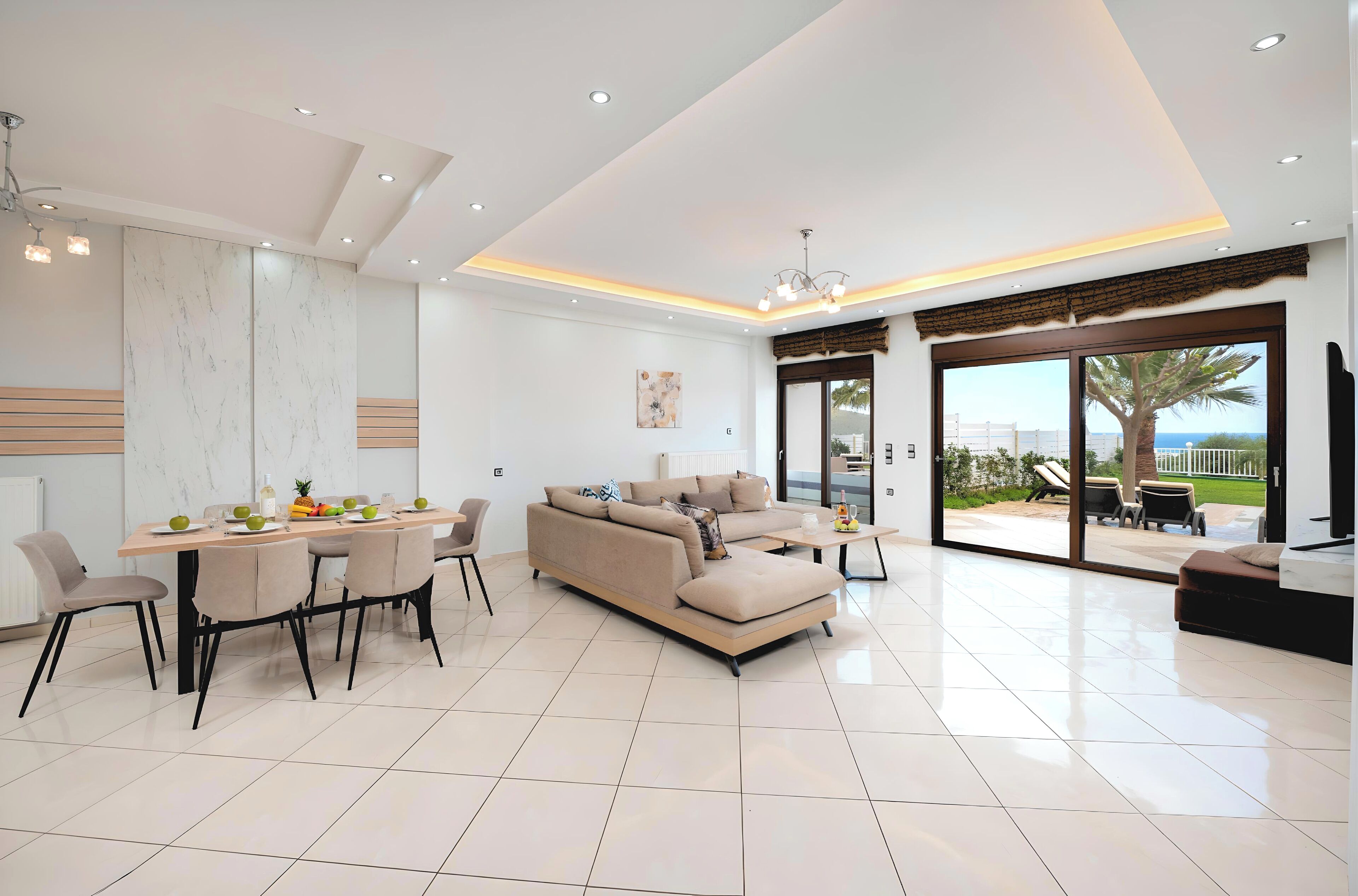 Uma sala de estar moderna com um sofá, uma mesa de jantar com cadeiras e uma janela grande com vista para o exterior.