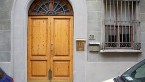 Une porte en bois à deux battants, surmontée d’une grille métallique, une plaque portant le numéro « 39 », et une voiture garée devant.