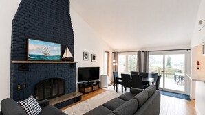 A living room with a fireplace, a TV, a sofa, and a dining area with a table and chairs.