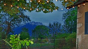 A view of a mountainous landscape with a building in the foreground and a string of lights above.