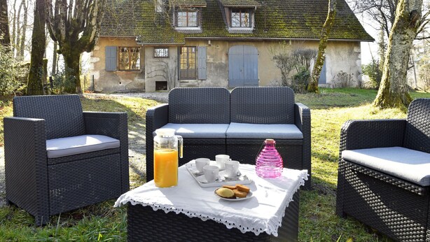 An outdoor seating area with wicker furniture and a table set with breakfast items.
