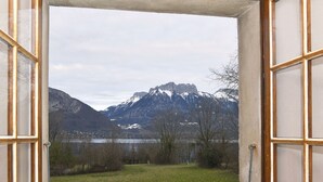 An open door leading to a room with a view of a mountainous landscape and a lake.