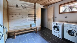 A laundry room with wooden walls, a bench, and two washing machines.