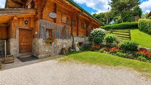 A wooden log cabin with a stone foundation, a wooden door, and a sign that reads 'Le Chalet.'