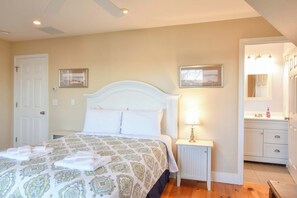 A bedroom with a bed, bedside tables, a nightstand, a mirror, and a door. - Newly updated spacious steps to water! (Eastham)