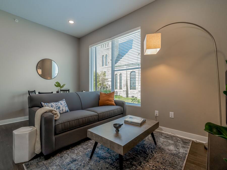 A modern living room with a grey sofa, a coffee table, a round mirror, and a floor lamp.