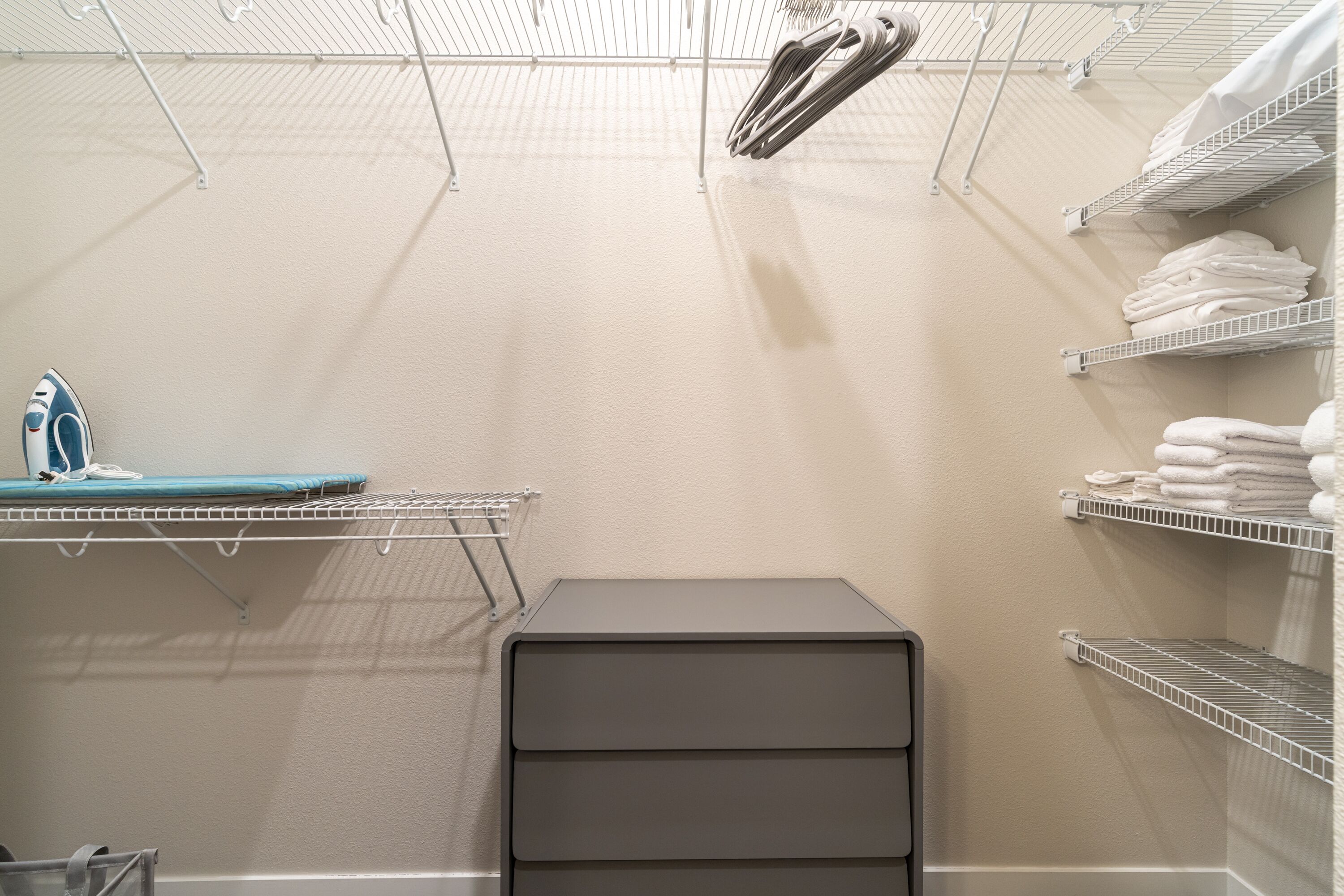 Un espace buanderie équipé d’étagères pour suspendre les vêtements, d’un étendoir et d’un meuble de rangement.