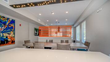 A modern conference room with a white table, grey chairs, and a colorful abstract painting on the wall.