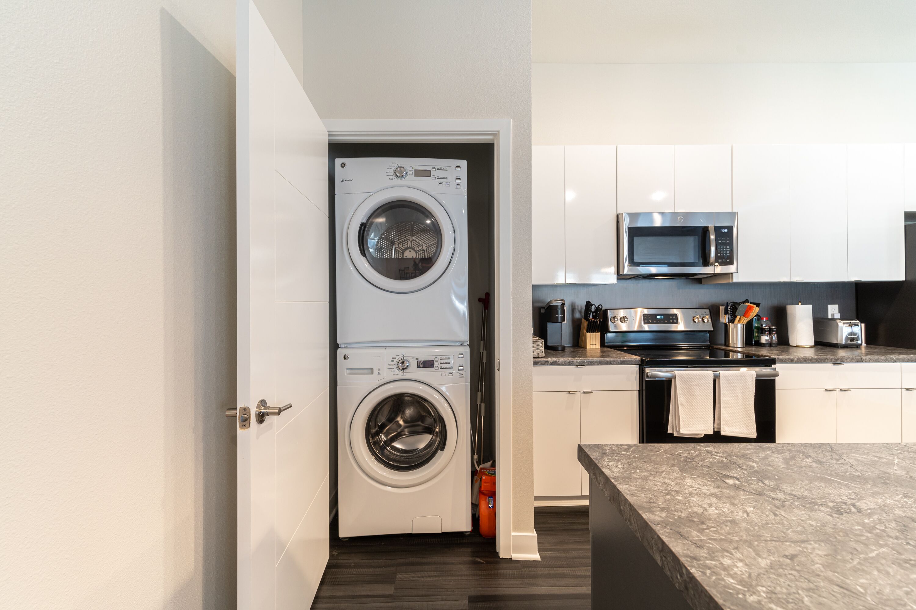 A compact kitchen with a washing machine, microwave, and stove.