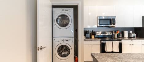 A compact kitchen with a washing machine, microwave, and stove.