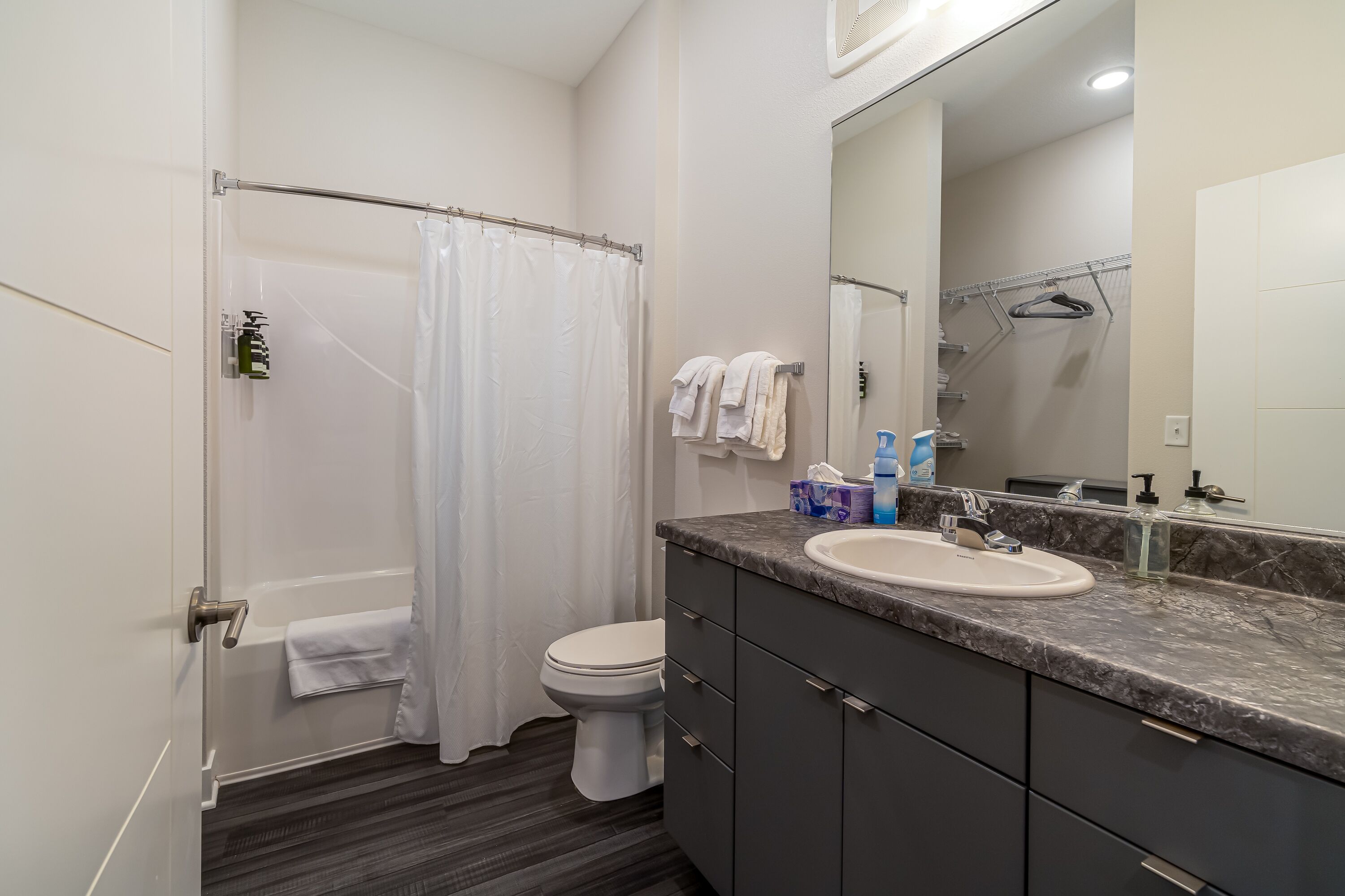 Une salle de bain moderne équipée d’une douche, de toilettes et d’un meuble-lavabo avec un évier et un miroir.