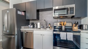 Een moderne keuken met roestvrijstalen apparatuur, een magnetron en een vaatwasser.